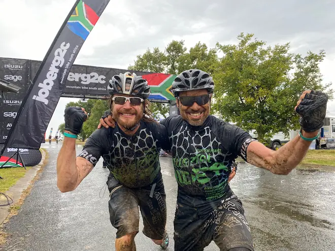 Ebbe und Albert vom Killertal Team feiern die Zieleinfahrt der Königsetappe Tag 3 der Joberg2C 2022 am Sterkfontein Dam, Südafrika