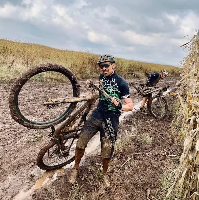 Killertal Rider Albert trägt sein Mountainbike durch den Schlamm — Königsetappe Tag 3 der Joberg2C 2022 in Südafrika