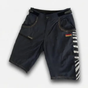Killertaler Herren Baggy Bike Shorts Epic Ride schwarz mit goldgelben Ziernähten und deutschem Flaggen-Patch — Cape Epic 2026, handgefertigt in Burladingen