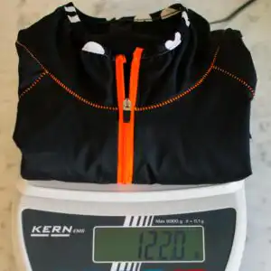 Ultraleichte Killertaler Damen Fahrrad Windjacke Etna in Schwarz auf der Präzisionswaage zeigt federleichte 122g mit Rückentasche (Referenz für Beispielgröße S).