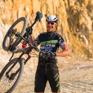 Mountainbiker mit Killertaler Herren Baggy-Bike Shorts und Radtrikot schwarz/gruen und hochgehobenem Mountainbike